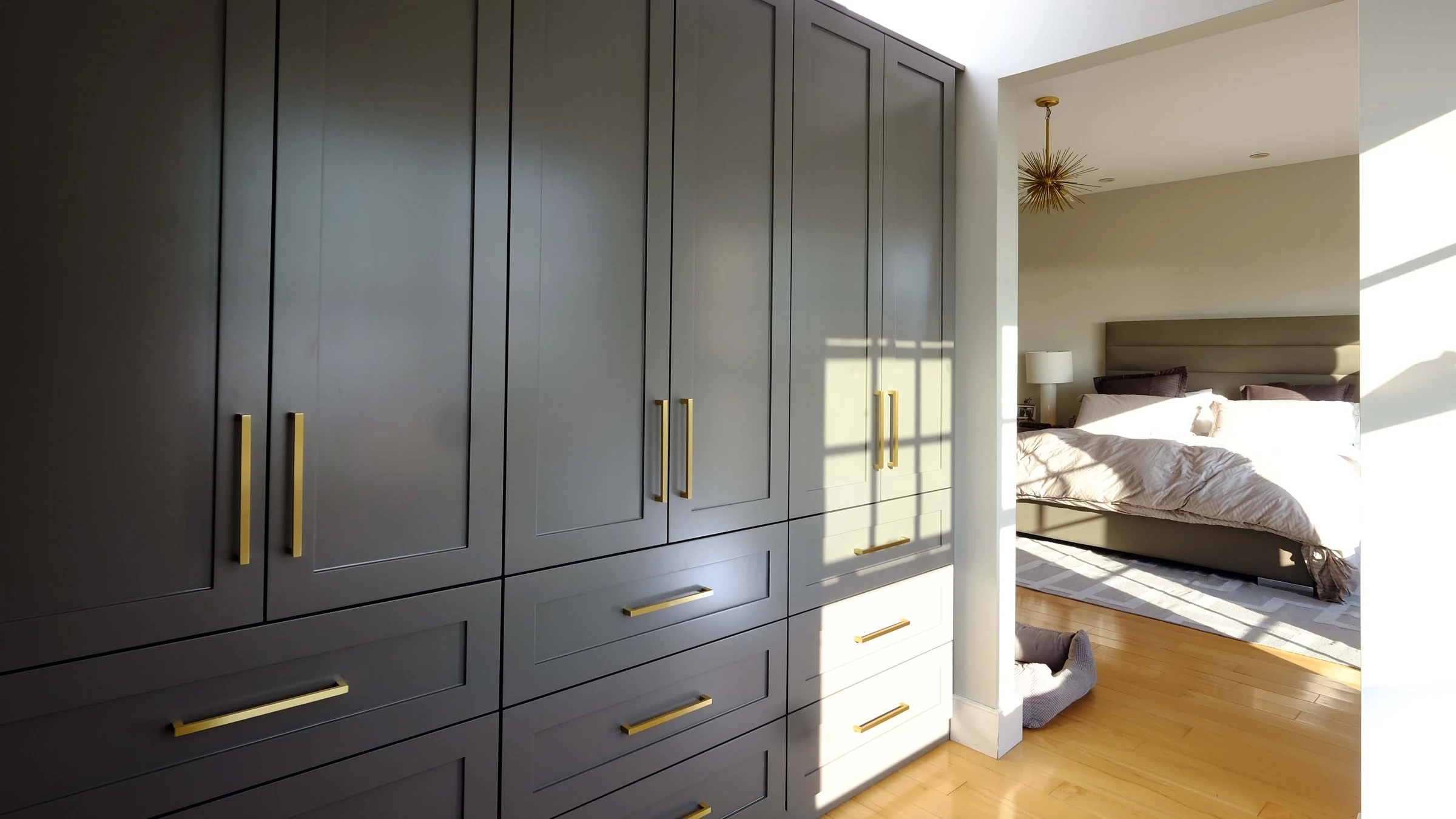 Charcoal wardrobes with brass handles and drawers in an East Hampton bedroom.